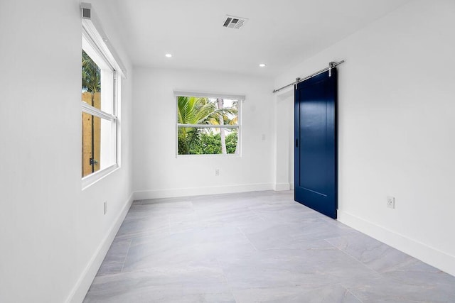 spare room featuring a barn door and plenty of natural light