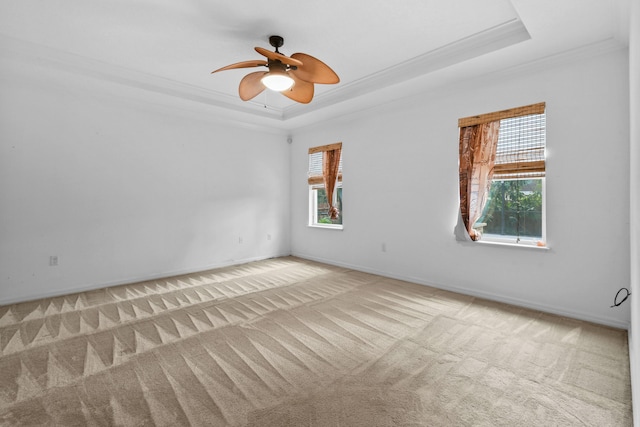 carpeted empty room featuring ceiling fan, a raised ceiling, and ornamental molding