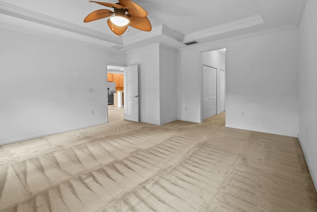 carpeted empty room with a tray ceiling, ceiling fan, and ornamental molding