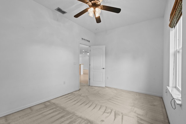 empty room featuring ceiling fan, plenty of natural light, and light carpet