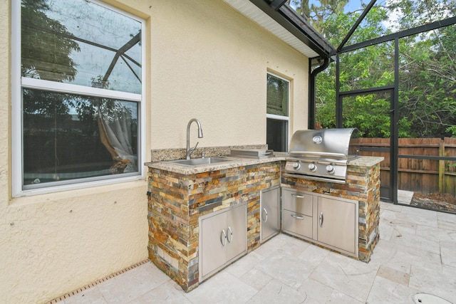 view of patio / terrace with grilling area, sink, glass enclosure, and exterior kitchen