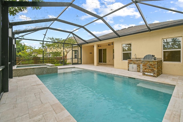 view of swimming pool with an in ground hot tub, an outdoor kitchen, ceiling fan, glass enclosure, and a patio area