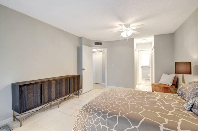 bedroom with a textured ceiling, ceiling fan, light tile patterned floors, and ensuite bathroom