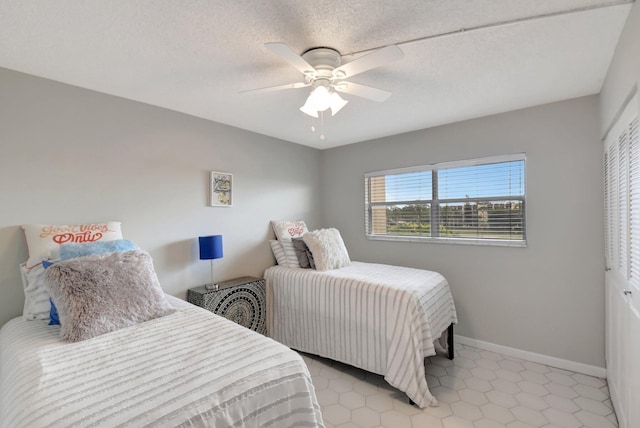 tiled bedroom featuring ceiling fan, a textured ceiling, and a closet