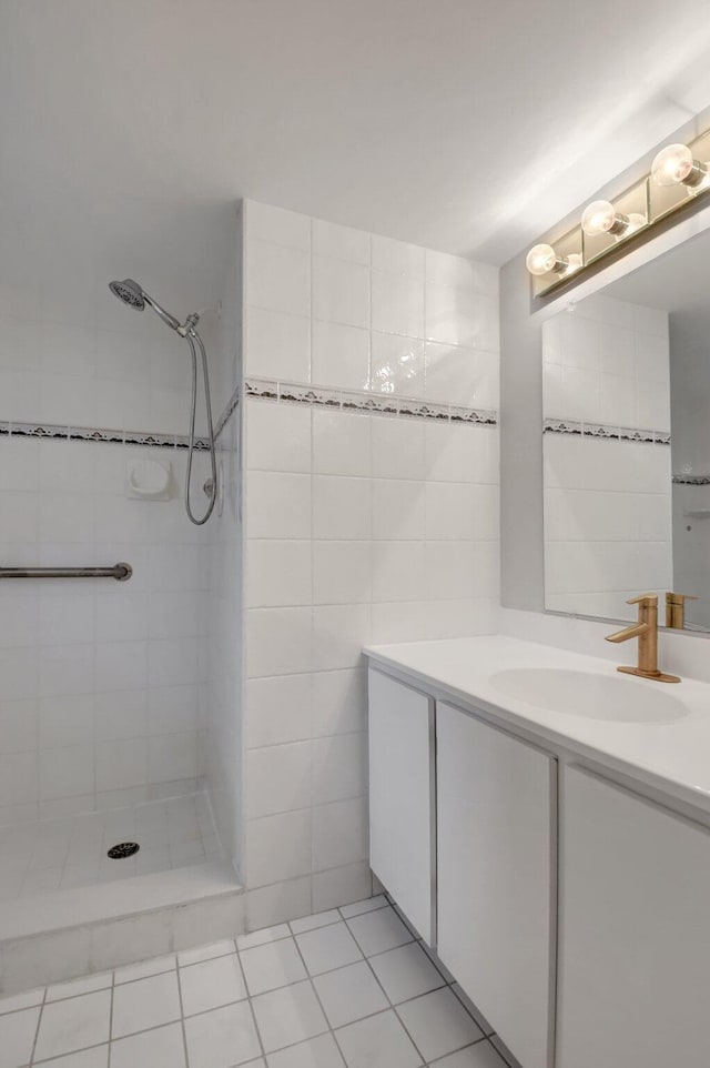 bathroom with tile patterned flooring, vanity, a tile shower, and tile walls