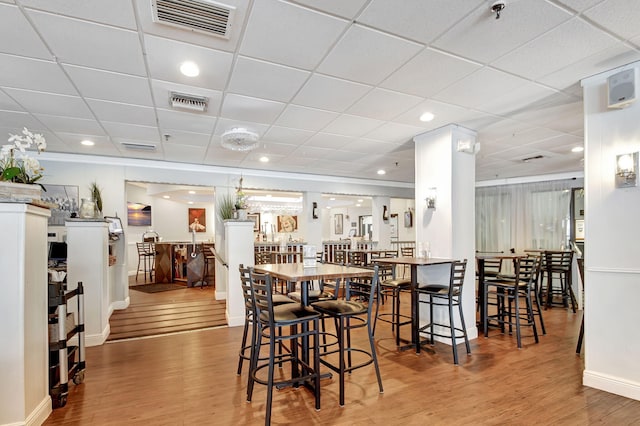 dining space with a paneled ceiling and light hardwood / wood-style floors