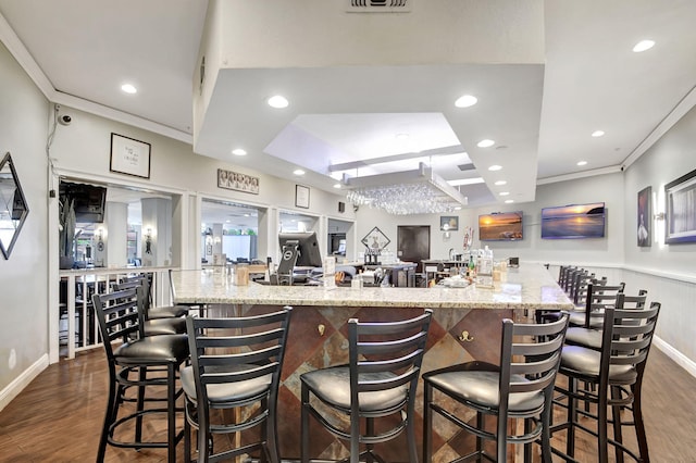 kitchen with a large island, a kitchen bar, ornamental molding, and dark wood-type flooring