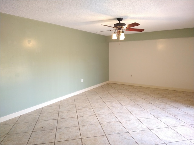 empty room featuring ceiling fan, light tile patterned floors, and a textured ceiling