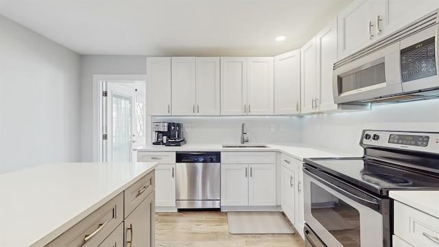 kitchen with light hardwood / wood-style floors, sink, white cabinetry, and stainless steel appliances