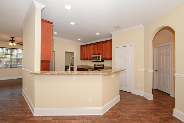 kitchen with a kitchen breakfast bar, kitchen peninsula, ceiling fan, and appliances with stainless steel finishes