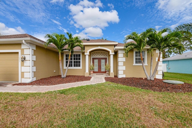 view of front of property featuring french doors, a garage, and a front lawn