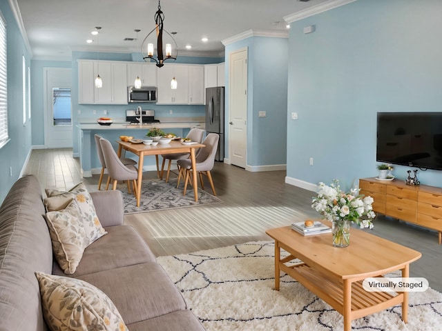 living room featuring hardwood / wood-style floors, sink, crown molding, and an inviting chandelier