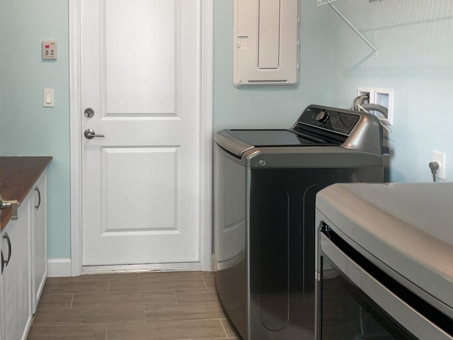 clothes washing area with electric panel and independent washer and dryer