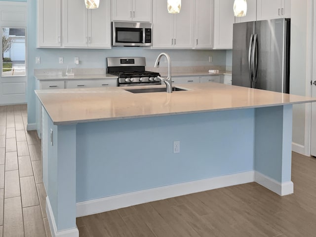 kitchen featuring stainless steel appliances, sink, pendant lighting, a center island with sink, and white cabinets