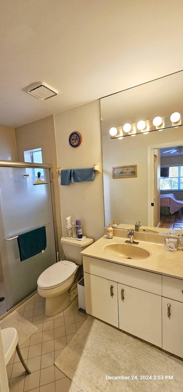 bathroom with tile patterned flooring, vanity, toilet, and a shower with shower door