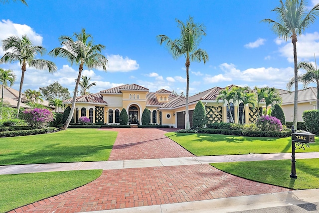 mediterranean / spanish house featuring a front yard and a garage