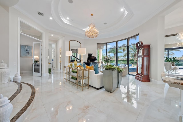 living room with a notable chandelier, ornamental molding, and a tray ceiling