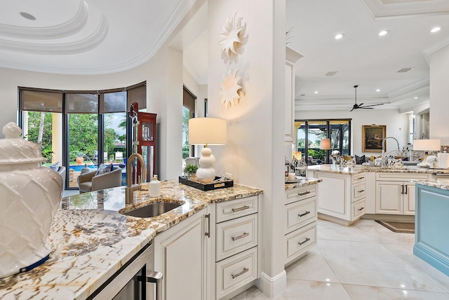 kitchen featuring crown molding, sink, ceiling fan, light stone countertops, and light tile patterned flooring