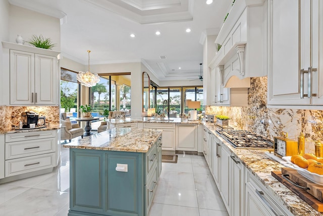 kitchen with backsplash, white cabinets, a kitchen island, and decorative light fixtures