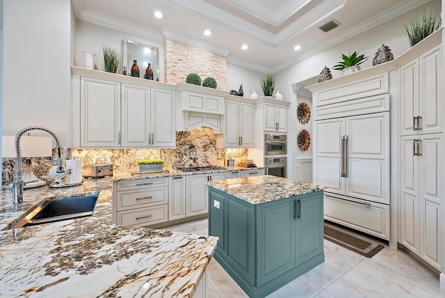 kitchen featuring white cabinets, light stone counters, a kitchen island, and sink