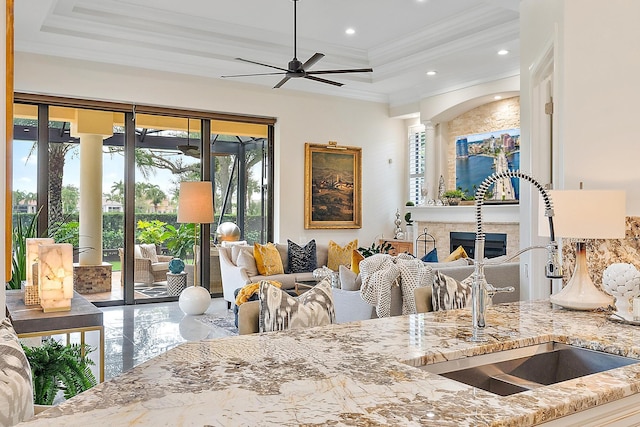 kitchen with a wealth of natural light, sink, light stone counters, and ornamental molding