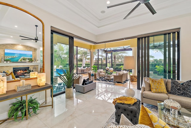 interior space with a raised ceiling, a fireplace, ceiling fan, and plenty of natural light