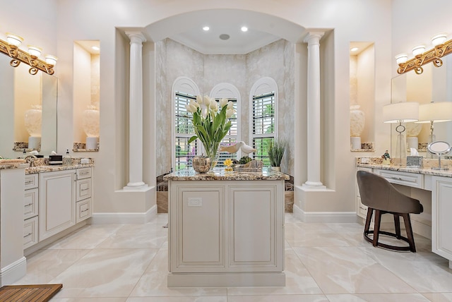 bathroom featuring decorative columns, vanity, a high ceiling, and ornamental molding