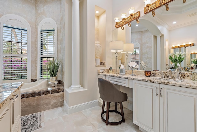 bathroom featuring a high ceiling, a relaxing tiled tub, decorative columns, crown molding, and vanity