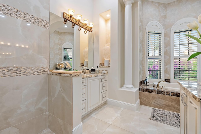 bathroom featuring vanity, ornate columns, and tiled tub