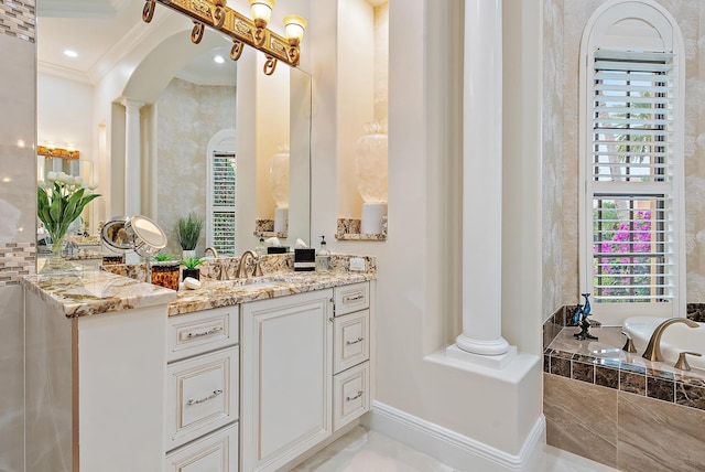 bathroom with vanity, ornate columns, crown molding, and tiled tub