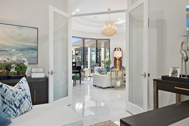 entryway featuring a raised ceiling, french doors, a chandelier, and ornamental molding