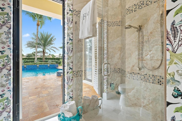 bathroom featuring toilet and a shower with door