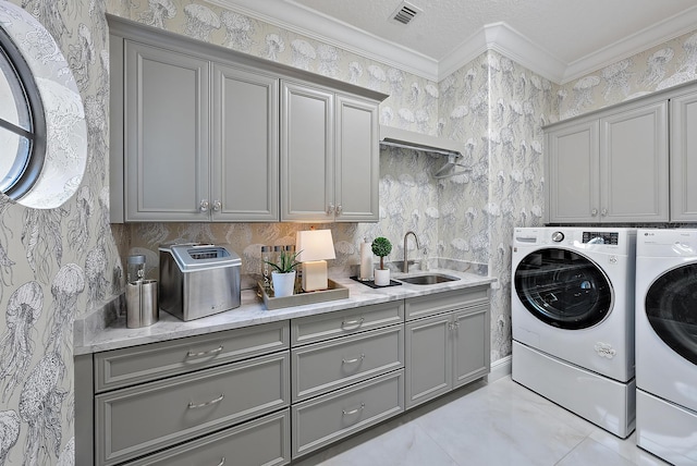 washroom featuring washer and clothes dryer, sink, cabinets, and ornamental molding