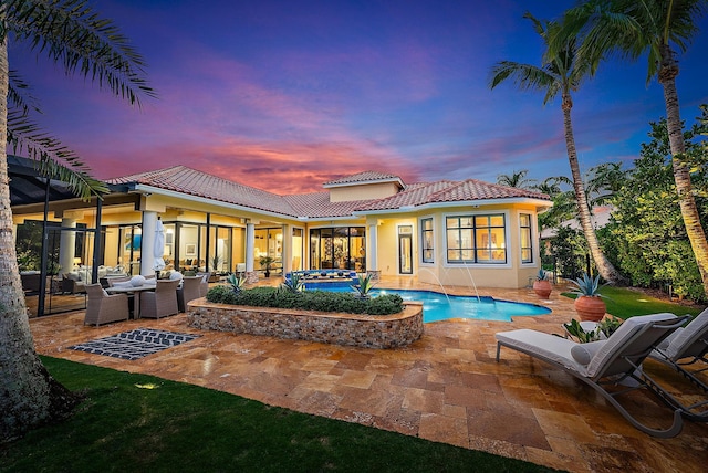 back house at dusk featuring a patio, an outdoor hangout area, and a pool with hot tub