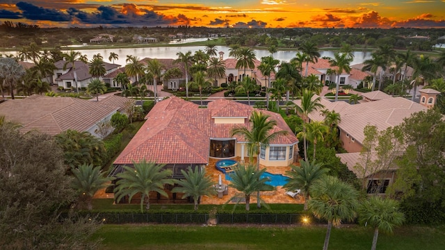 aerial view at dusk featuring a water view