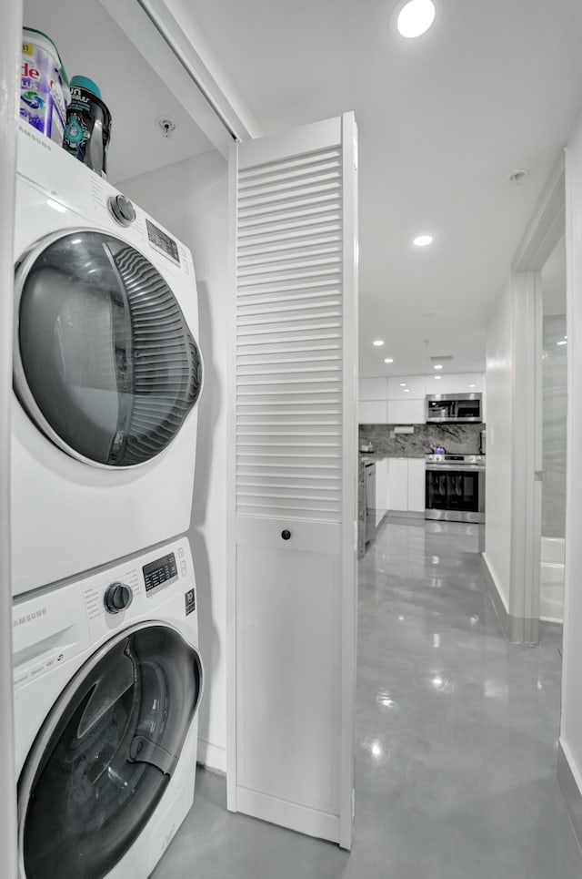 clothes washing area featuring stacked washer and clothes dryer