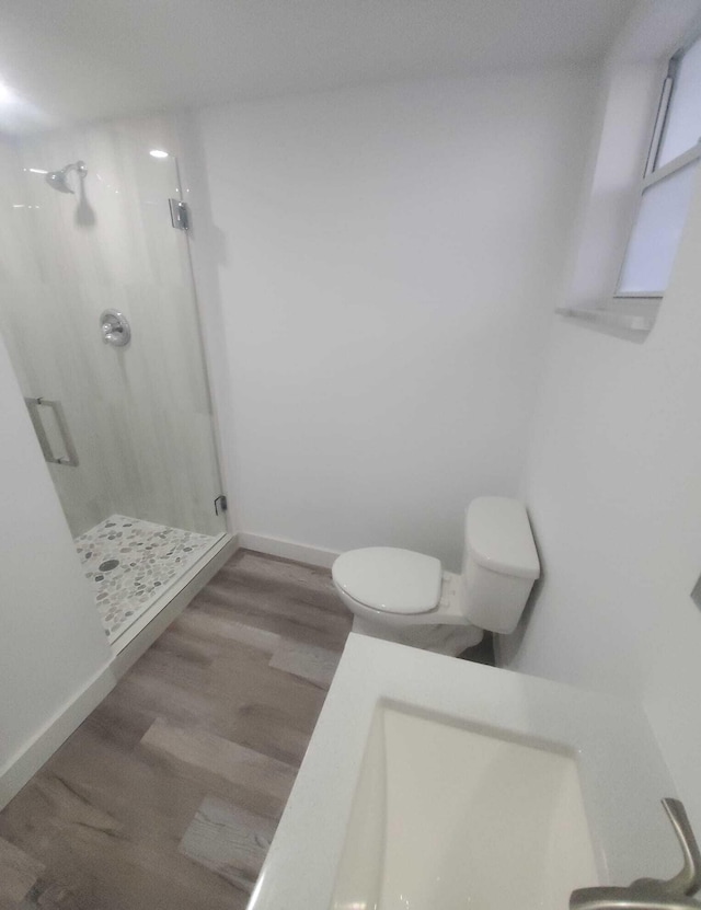 bathroom with hardwood / wood-style flooring, an enclosed shower, and toilet