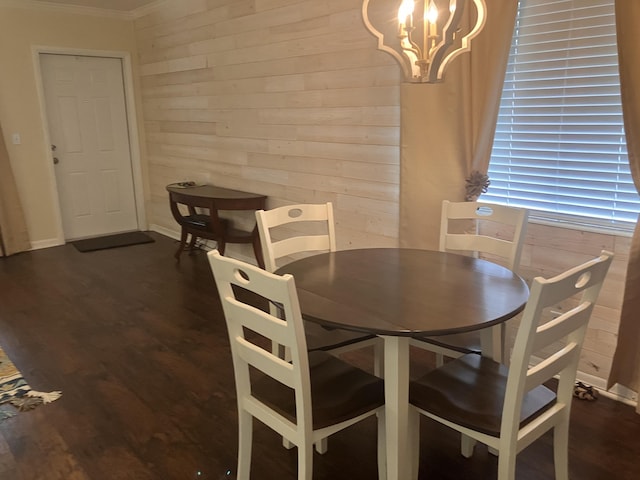 dining area with wood walls, dark hardwood / wood-style flooring, ornamental molding, and an inviting chandelier