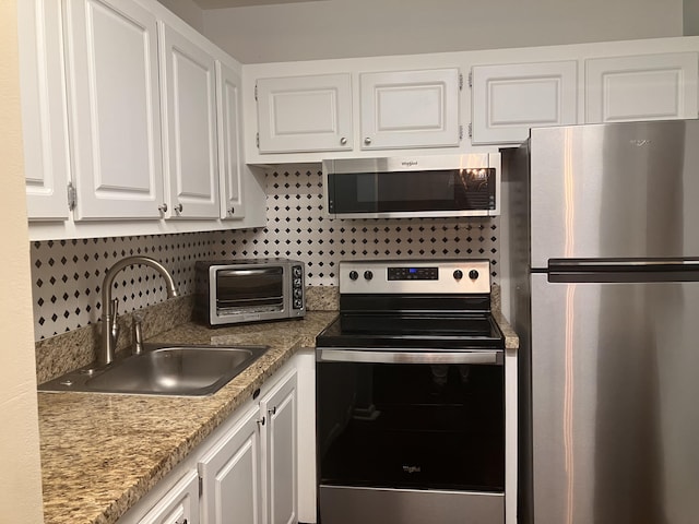 kitchen featuring white cabinets, stainless steel appliances, tasteful backsplash, and sink