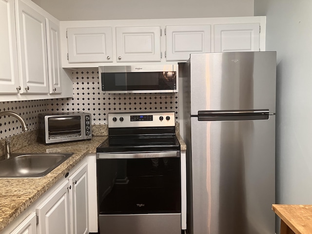 kitchen with white cabinets, appliances with stainless steel finishes, tasteful backsplash, and sink