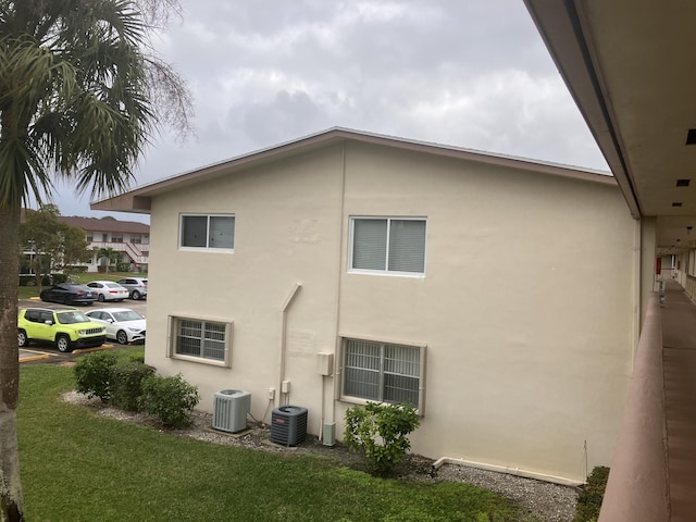 exterior space featuring central air condition unit and a lawn