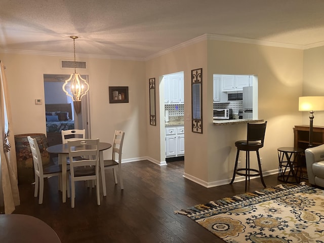 dining room featuring a textured ceiling, a chandelier, dark hardwood / wood-style floors, and ornamental molding