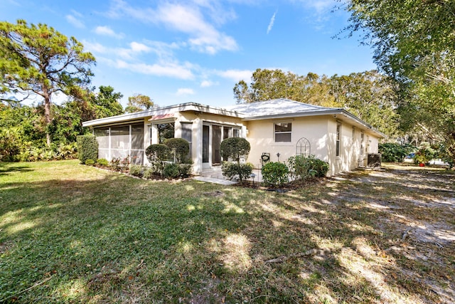 rear view of house with a lawn and a sunroom