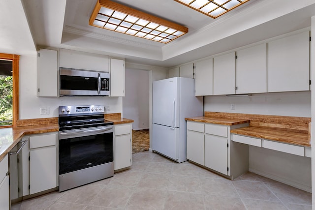 kitchen with white cabinetry, a tray ceiling, crown molding, and appliances with stainless steel finishes