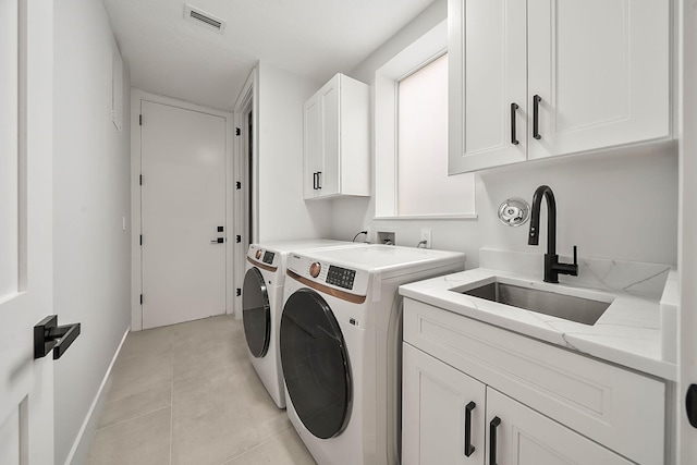 laundry room featuring cabinets, washing machine and dryer, light tile patterned floors, and sink