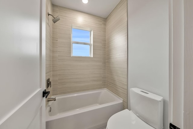 bathroom with toilet and tiled shower / bath