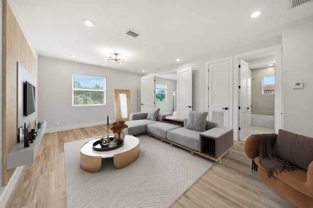 living room with a chandelier, light hardwood / wood-style flooring, and a healthy amount of sunlight