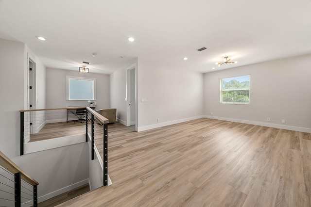 spare room featuring light hardwood / wood-style flooring and a notable chandelier