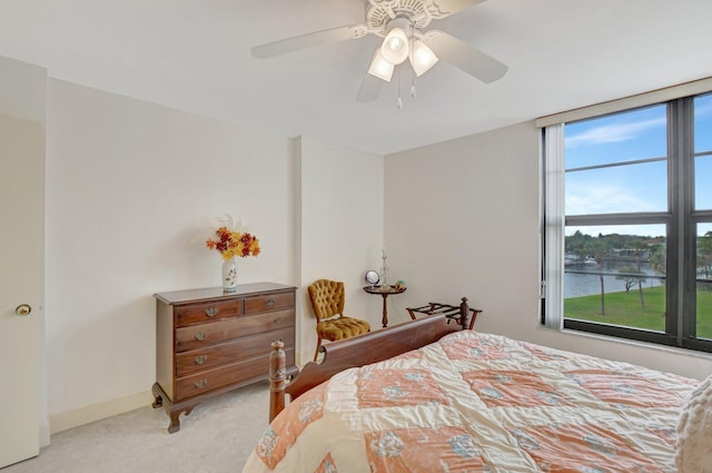 bedroom with a water view, light carpet, and ceiling fan