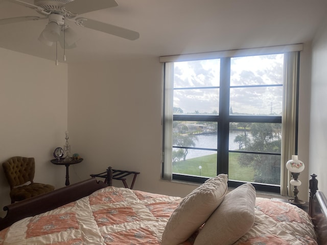 bedroom featuring ceiling fan, a water view, and multiple windows